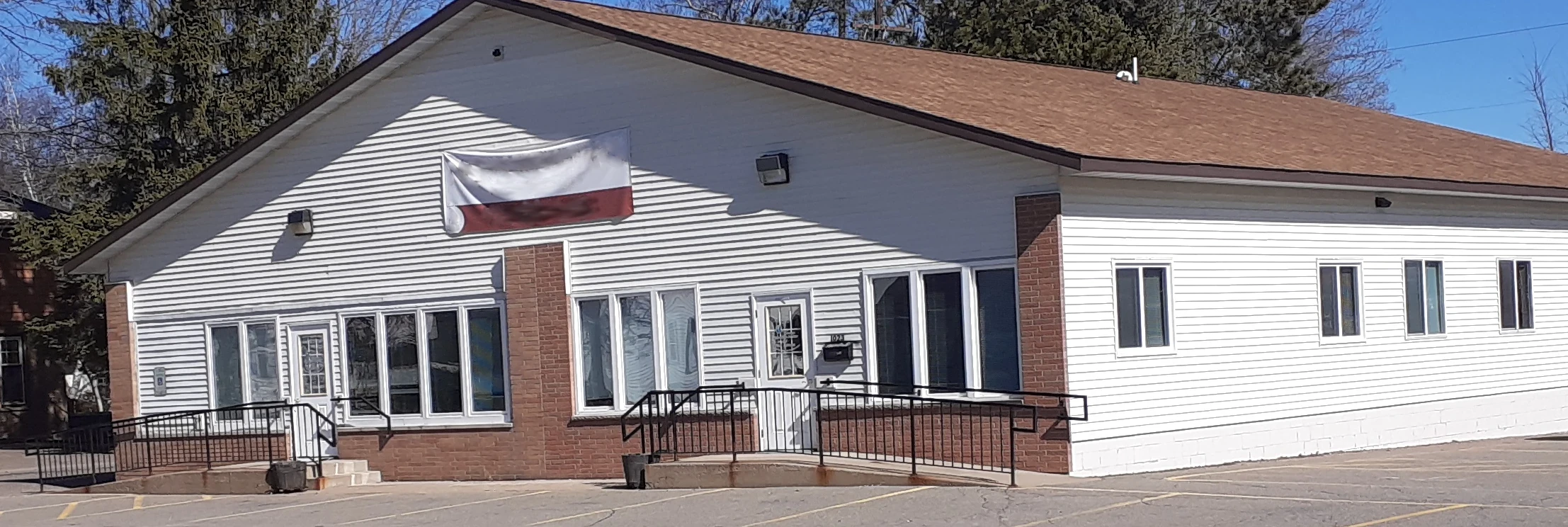 A picture of a building with a banner in the middle. There are two doors on the front of the building.